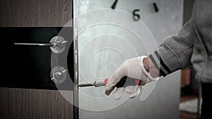 A carpenter installs a door lock on an interior door  a handyman repairs a door  a man with a screwdriver in his hand.