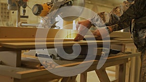 Carpenter or Joiner sawing a wooden board with a circular saw in workshop of furniture manufacturing