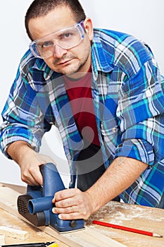 Carpenter or joiner working with electric planer photo