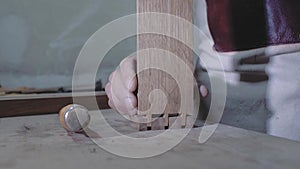 A carpenter joins two wooden parts made using the technology of a dovetail with a hammer. Detail of a carpenter with dovetail