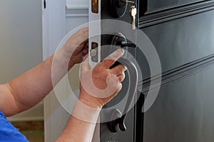 carpenter at lock installation with close up human hend hold doorhandle. into interior wood door