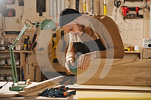 Carpenter is making furniture on order in a workshop