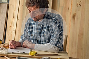 Carpenter making woodwork project notes on clipboard paper
