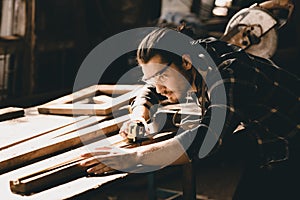 Carpenter man attend to making masterpiece woodworks handcrafted furniture fine measure in wood workshop