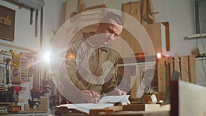 A carpenter man calculates the cost of a wood product. Carpentry workshop.