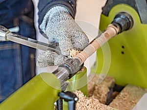 Carpenter man is carving the wooden stick. Spinning wood wheel machine.