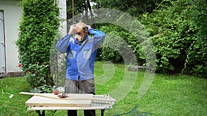 Carpenter man put protective glasses and mask on and start polishing wood board