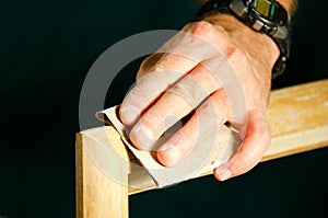 Carpenter man sanding wood molding for door frame