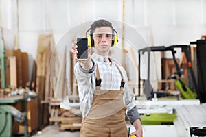 Carpenter man show the mobile phone isolated in carpentry background