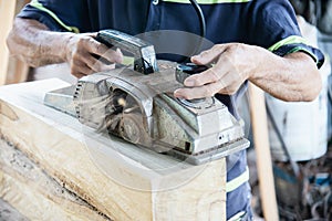 Carpenter man is using electrical wood planer machine