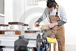 Carpenter man works with wooden planks in the joinery, measure with meter, with computer numerical control center, cnc machine,