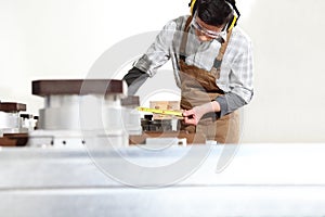 Carpenter man works with wooden planks in the joinery, measure with meter, with computer numerical control center, cnc machine,