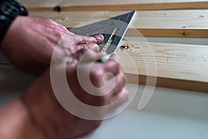 Carpenter marking a pine wood board with a speed square