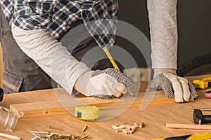 Carpenter marking pine wood plank for cutting