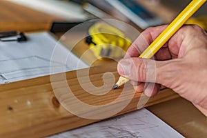 Carpenter marking pine wood plank for cutting