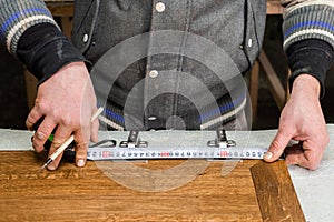 The carpenter measures the distance for the hinges in the cabinet door