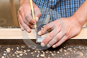 The carpenter measures the distance with a pencil using a square