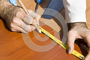 Carpenter measures the distance using a measure and marks with a carpenter`s pencil.