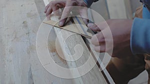 A carpenter measures a wooden board with a square at an angle and marks the dimensions with a pencil. 4k. 4k video. slow motion.