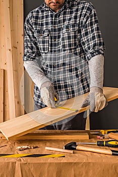 Carpenter is measuring pine wood plank
