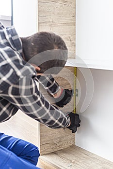 Carpenter measuring shelves that are parts of new kitchen with meter