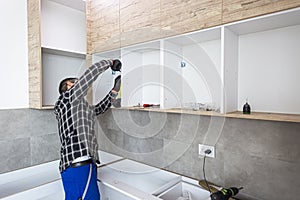 Carpenter measuring shelves that are parts of new kitchen with meter