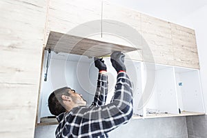 Carpenter measuring shelves that are parts of new kitchen with meter