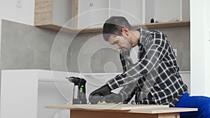 Carpenter measuring shelves that are parts of new kitchen with meter