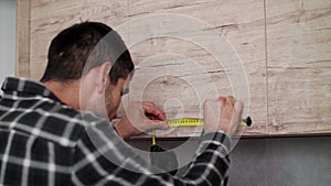 Carpenter measuring shelves that are parts of new kitchen with meter