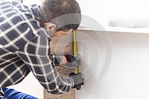 Carpenter measuring shelves that are parts of new kitchen with meter