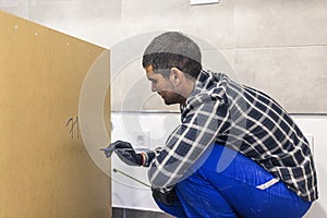 Carpenter measuring shelves that are parts of new kitchen with meter