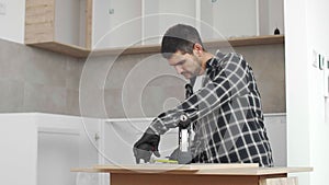 Carpenter measuring shelves that are parts of new kitchen with meter