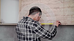 Carpenter measuring shelves that are parts of new kitchen with meter