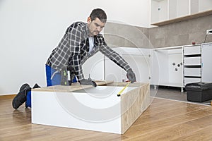 Carpenter measuring shelves that are parts of new kitchen with meter