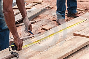 Carpenter measuring the size of a wooden plank for cut