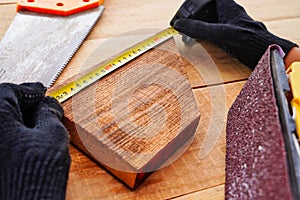 Carpenter measuring wooden plank at workplace with gloves. Making handmade products from wood.