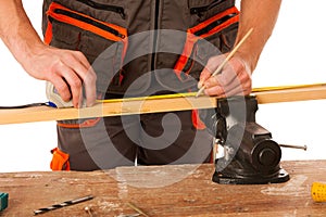 A carpenter measuring a wooden plank in a workshop isolated over
