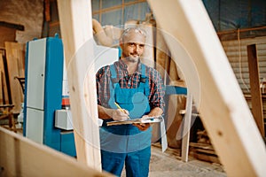 Carpenter with notebook, wood processing, factory