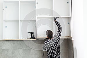 The carpenter places the newly assembled kitchen shelves in the intended place