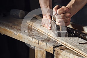 Carpenter planing a plank of wood with a hand plane