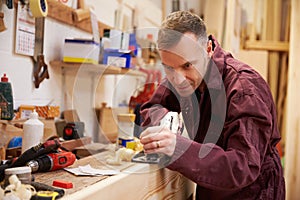 Carpenter Planing Wood In Workshop