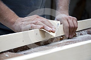 Carpenter polishes wood with sandpaper