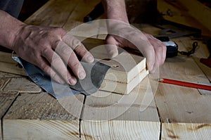 Carpenter polishes wood with sandpaper