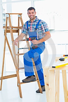 Carpenter with power drill climbing ladder at construction site