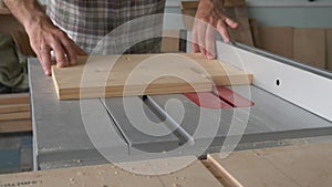 A carpenter processes a wooden blank on a circular saw in a carpentry workshop.