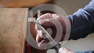 A carpenter removes chamfer from a piece of wood with a chisel. woodworker working with a chisel. hand carpentry tools