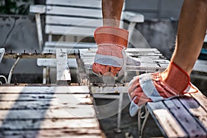 The carpenter is repairing the table. By wearing gloves to prevent injury