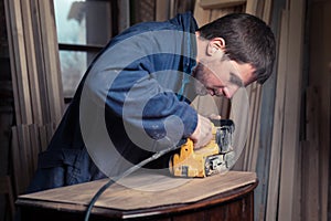 Carpenter restoring furniture with belt sander