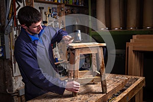 Carpenter restoring Wooden Stool Furniture in his workshop.