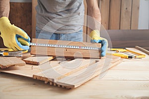 Carpenter with ruler measuring wood plank
